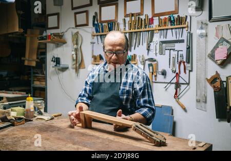 Più lustra facendo la tastiera della chitarra mentre si sta in officina Foto Stock