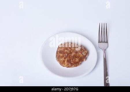 Polpa di carne cotta su un piatto bianco accanto a una forchetta isolato su sfondo bianco, primo piano, spazio per la copia Foto Stock