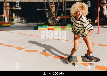 Donna bionda sicura skateboarding sul sentiero durante la giornata di sole Foto Stock