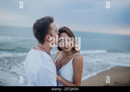 Uomo che baciava la donna mentre si trova in spiaggia Foto Stock