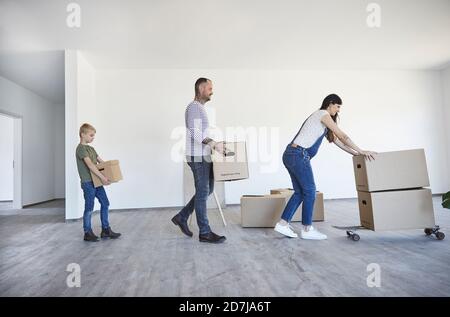Famiglia che tiene scatole di cartone sullo skateboard in casa nuova Foto Stock