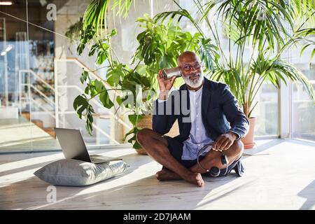 L'uomo maturo che ascolta da Tin può telefonare mentre si siede a. casa Foto Stock