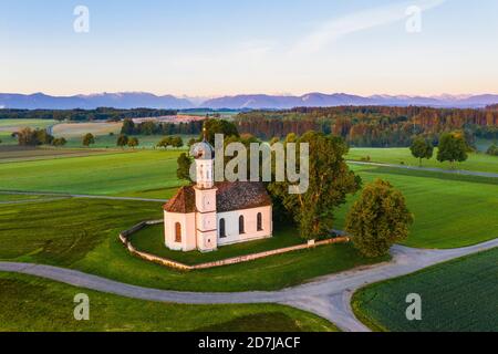 Germania, Baviera, Etting, Drone vista della chiesa di Sant'Andrea circondata da campi verdi all'alba Foto Stock