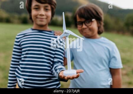 Sorridi i ragazzi che tengono il giocattolo del mulino a vento mentre sono in piedi in cortile Foto Stock