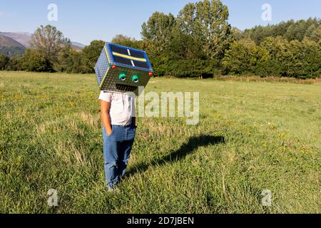 Ragazzo con scatola di cartone sorridente sul volto in piedi in prato Foto Stock