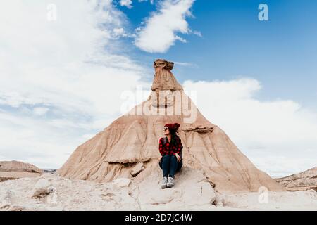 Spagna, Navarra, turista femminile seduto di fronte alla formazione di pietra arenaria in Bardenas Reales Foto Stock