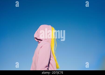 Donna che guarda via mentre si sta in piedi contro il cielo chiaro sul sole giorno Foto Stock