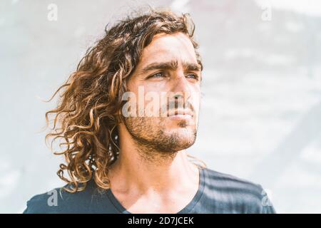 Primo piano di un giovane pensieroso che guarda lontano contro il muro bianco Foto Stock