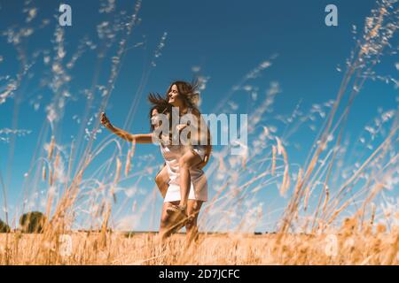 Donna che prende selfie mentre piggybacking su campo agricolo Foto Stock