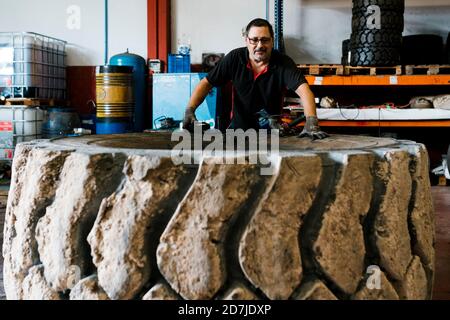 Meccanico che esamina la ruota del camion mentre si trova in officina di riparazione auto Foto Stock