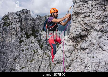 Alpinista maschile con arrampicata su corda in montagna, Alpi europee, Lecco, Italia Foto Stock