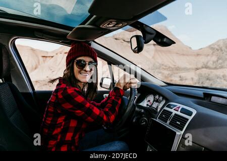 Ritratto di turista femminile seduto in auto e sorridente a. fotocamera Foto Stock