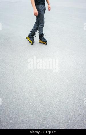 Gambe di giovane uomo inline pattinaggio su strada Foto Stock
