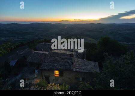 Case in montagna contro il cielo durante il tramonto, Marche, Italia Foto Stock