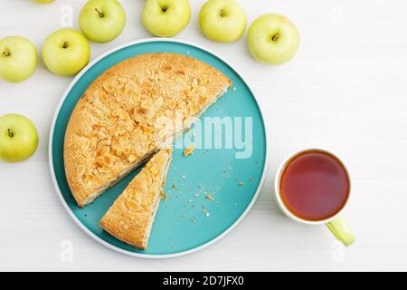 Pasticceria fatta in casa. Torta di mele con petali di mandorle e tazza di tè su tavolo di legno bianco. Vista dall'alto. Foto Stock