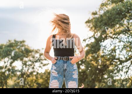 Giovane donna con lunghi capelli biondi in piedi contro il cielo Foto Stock