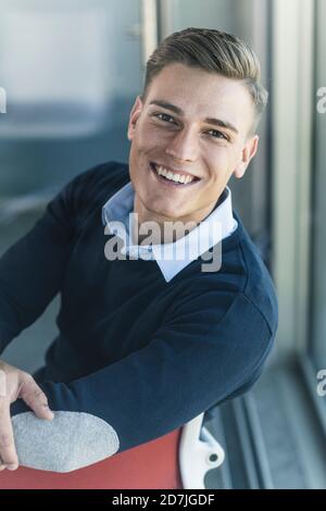 Primo piano di sorridente bell'uomo d'affari che si siede in ufficio Foto Stock