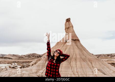 Spagna, Navarra, Ritratto di donna turistica in piedi con braccia sollevate di fronte alla formazione di pietra arenaria in Bardenas Reales Foto Stock