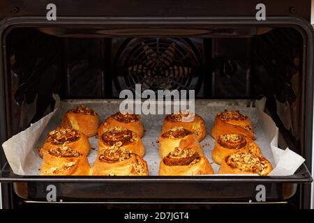 Dolci alla cannella fatti in casa da impasto di lievito cotto in un forno a casa. Messa a fuoco superficiale. Foto Stock