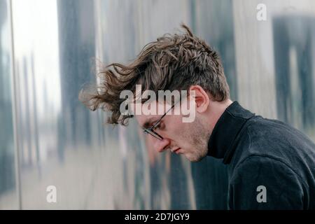 Primo piano di un uomo attento che indossa occhiali che guardano verso il basso Foto Stock