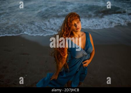 Donna con gli occhi chiusi in piedi sulla spiaggia Foto Stock