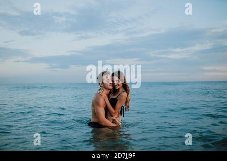 Giovane uomo e donna si abbracciano mentre si sta spiaggia Foto Stock