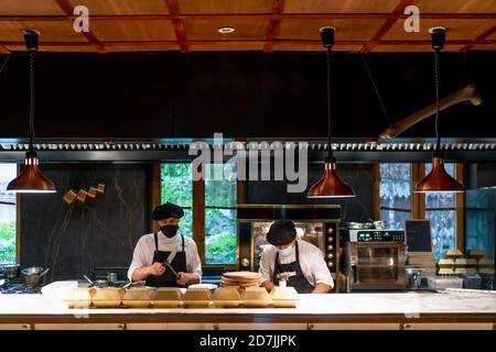 Gli chef indossano una maschera protettiva in piedi nel ristorante Foto Stock