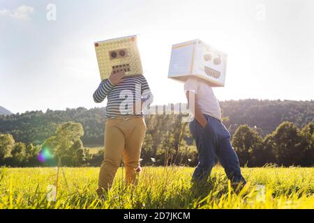 Ragazzo che gioca mentre copre il viso con scatola di cartone robot Foto Stock