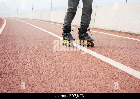 Gambe di giovane uomo inline pattinare sul ponte in città Foto Stock