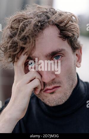 Primo piano ritratto del triste giovane uomo con testa in mano Foto Stock