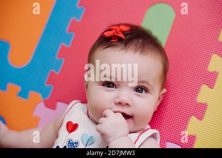 Primo piano ritratto di cute baby girl con dito in bocca sdraiato su un commediografo a casa Foto Stock