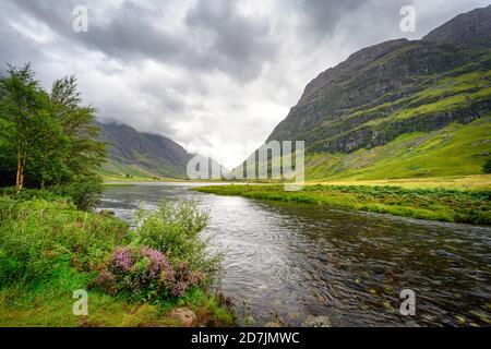 Nuvole grigie sul fiume che scorre attraverso Glen Coe Foto Stock