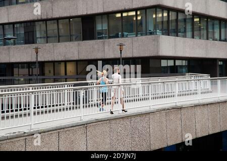 Donna che fa jogging da uomo d'affari sul ponte pedonale del centro cittadino Foto Stock