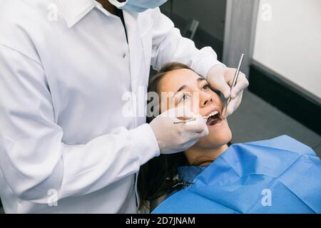 Dentista maschile che ispeziona la cavità orale di una giovane paziente femminile a. clinica Foto Stock