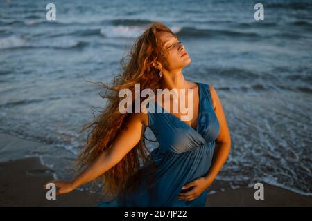 Bella donna che balla in spiaggia durante il tramonto Foto Stock