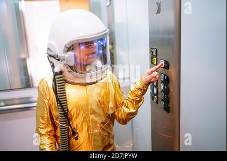 Il ragazzo indossa la tuta spaziale premendo i pulsanti nell'ascensore Foto Stock