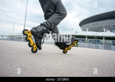 Gambe di giovane uomo inline pattinaggio su strada contro il cielo Foto Stock