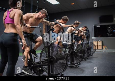 Atleti seduti in bicicletta mentre si allenano in palestra Foto Stock
