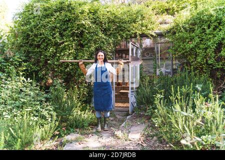 Donna matura che tiene la pala mentre si sta in piedi nel cortile posteriore sopra giorno di sole Foto Stock