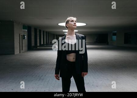 Uomo traslucido che indossa una tuta nera in piedi sul pavimento nel seminterrato Foto Stock