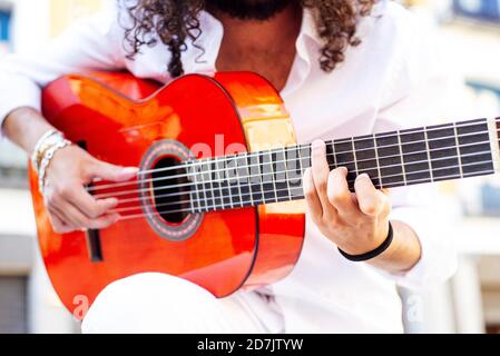 Uomo seduto e suonando la chitarra in città Foto Stock