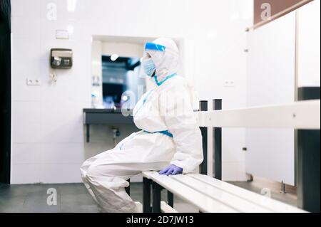 Operatore sanitario seduto su panca in sala medica in ospedale Foto Stock