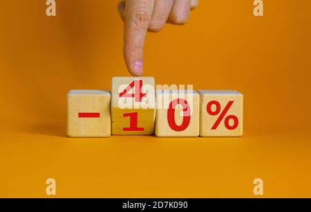 Mano trasforma un cubo e cambia l'espressione '-10 percento' in '-40 percento'. Splendido sfondo arancione, spazio per la copia. Concetto aziendale. Foto Stock