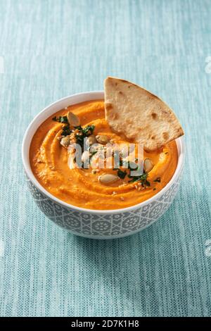 Hummus di zucca in ciotola e pita pane su sfondo blu Foto Stock