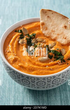 Hummus di zucca in ciotola e pita pane su sfondo blu Foto Stock