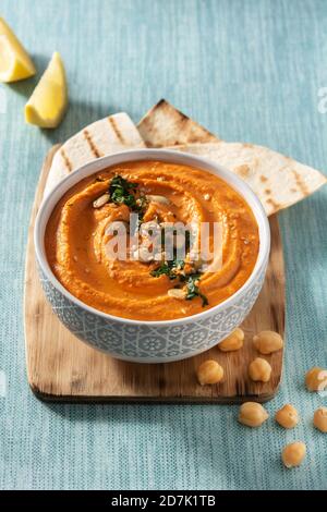 Hummus di zucca in ciotola e pita pane su sfondo blu Foto Stock