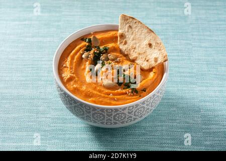 Hummus di zucca in ciotola e pita pane su sfondo blu Foto Stock