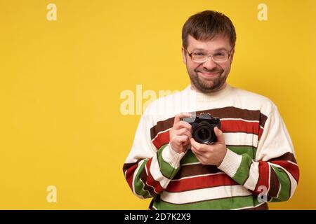 giovane caucasico che tiene la fotocamera prendere studio fotografico per fare foto. Foto Stock