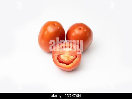 Un pomodoro a fette e due pomodori pieni su fondo bianco Foto Stock