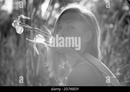 Primo piano di una donna bionda faccia con un giglio su una palude al tramonto. Foto Stock